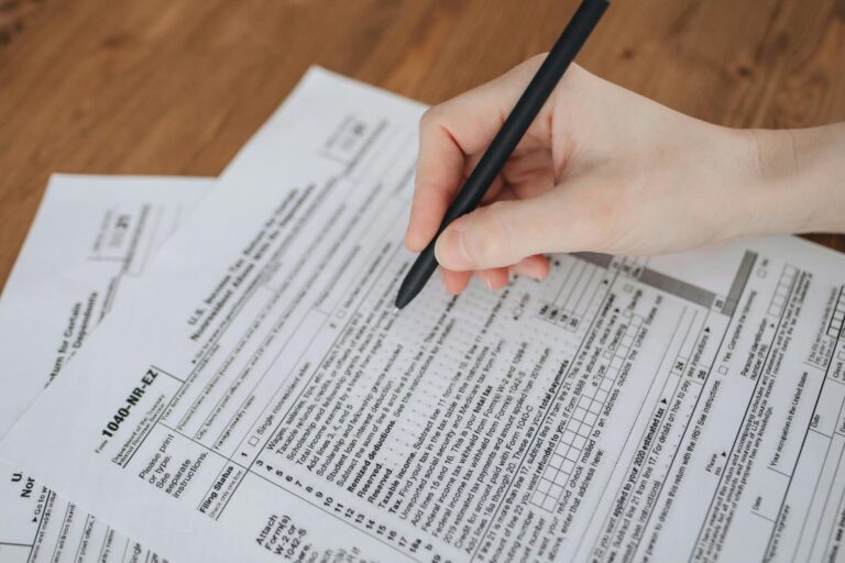 Person's hand with a pen, filling out tax forms